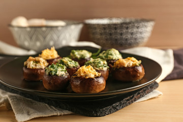 Plate with tasty stuffed mushrooms on table