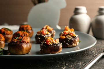 Plate with tasty stuffed mushrooms on table, closeup
