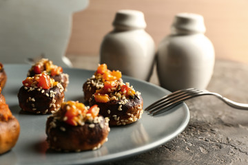 Plate with tasty stuffed mushrooms on table, closeup