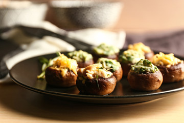Plate with tasty stuffed mushrooms on table, closeup