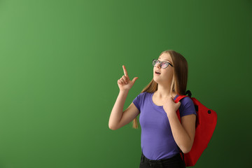 Schoolgirl with raised index finger on color background