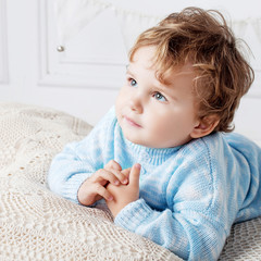 Portrait of happy adorable baby boy on the bed in his room. Copy space