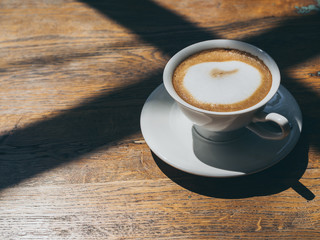 Hot coffee in round white ceramic cup on wooden table background