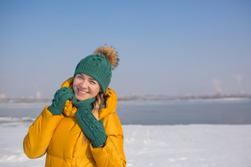 Fototapeta na wymiar Young woman in yellow down jacket poses and smiles outside