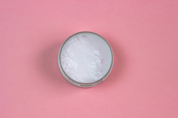 A jar of natural cosmetic cream on a pink background.