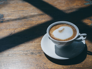 Hot coffee in round white ceramic cup on wooden table background