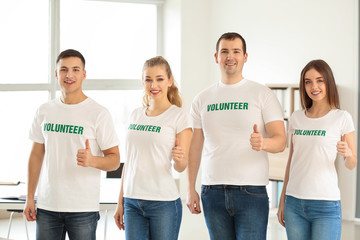 Team of young volunteers showing thumb-up indoors