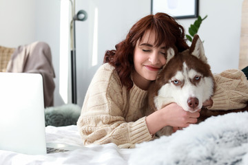 Young woman with her cute dog lying on bed at home © Pixel-Shot