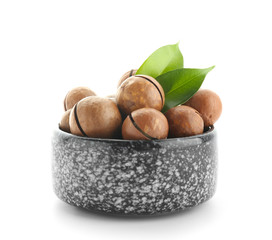 Bowl with macadamia nuts on white background