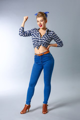 Beautiful pin-up woman showing muscles on grey background