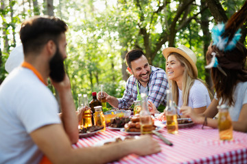 Group of happy friends eating and drinking beers at barbecue dinner