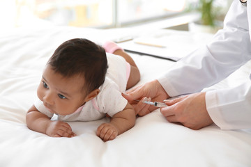 Pediatrician giving little baby an injection in clinic