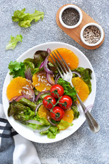 Detox nutrition. Salad with orange, onion and seeds on the kitchen table. View from above.