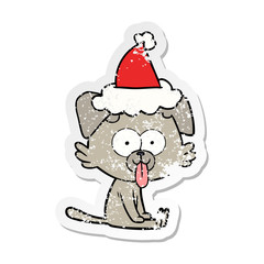 distressed sticker cartoon of a sitting dog with tongue sticking out wearing santa hat