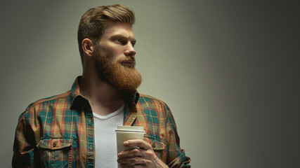 Bearded man with ginger hair drinking cappuccino coffee to go