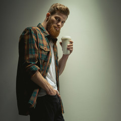Confident bearded hipster holding cup of coffee