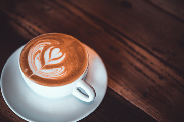 Latte arts coffe. White cup of hot coffee on wooden table. Cafe with barista art concept.