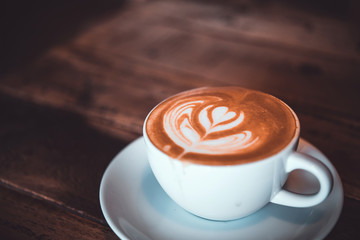 Latte arts coffe. White cup of hot coffee on wooden table. Cafe with barista art concept.