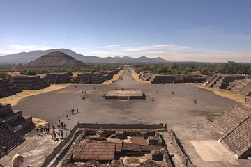 Stone pyramids, hills, mountains, trees and bushes at Teotihuacan near Mexico City on clear day with blue sky and white clouds