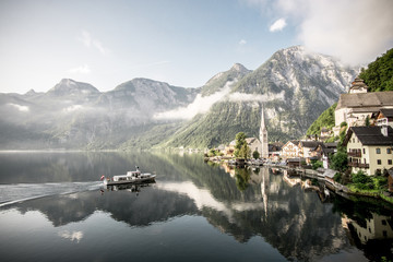 Boot fährt im Sonnenaufgang auf einem See nach Hallstatt in Österreich ein.