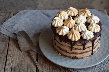 Chocolate cake decorated with rosettes of meringue cream: chocolate-nut biscuit, caramel cream. Homemade baking.