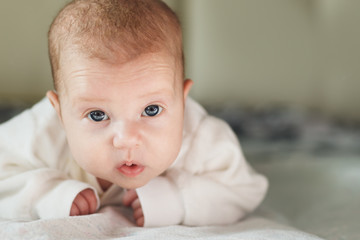 Adorable baby on the bed in the sunny bedroom.