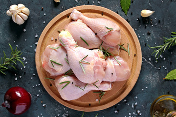 Raw uncooked chicken legs with ingredients for cooking, drumsticks on wooden board. Top view with copy space.