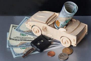 Money, Wooden Toy Car and key vehicle on Silver background.