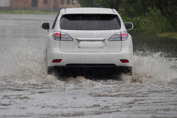 Fototapeta na wymiar car rides in heavy rain on a flooded road
