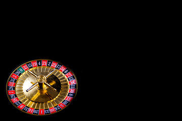 Roulette table in casino, with many games and slots, roulette wheel in the foreground. Black background for text