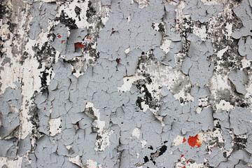 Old shabby cracked wall with old layers of gray paint