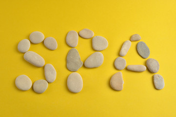 Spa stones and word spa on yellow background