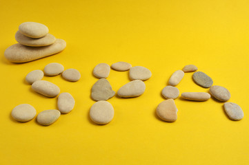 Fototapeta na wymiar Spa stones and word spa on yellow background