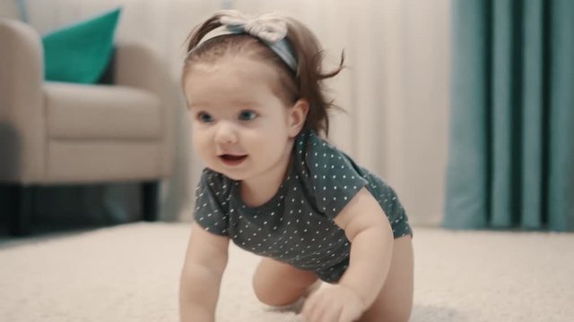 Happy baby girl crawling on floor, close up