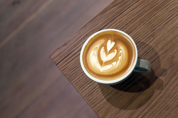 a cup of latte art coffee on wooden background