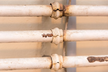 three white and rusty pipes at a white wall 
