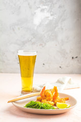 Shrimps tempura with lime in light plate and glass of beer