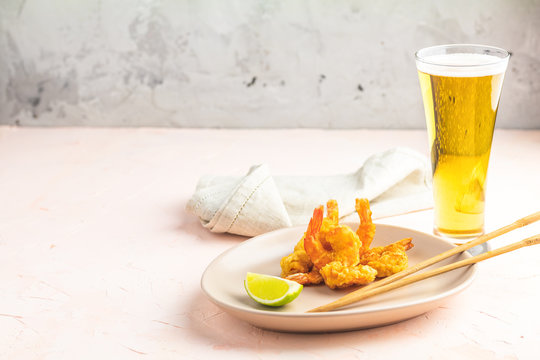 Shrimps tempura with lime in light plate and glass of beer