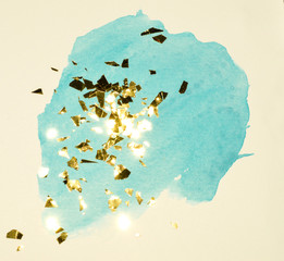 Abstract blue watercolor splash and golden glitter, pieces of foil, background in vintage nostalgic colors.
