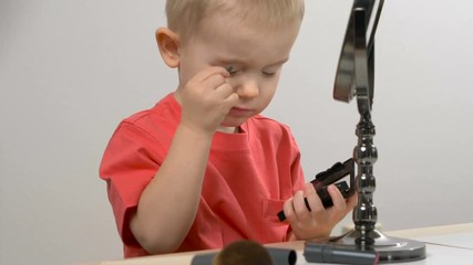 Cute kid playing with mom's cosmetics. Closeup portrait. Beauty, makeup concept