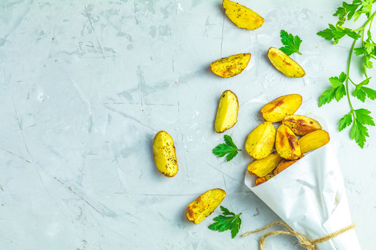 Baked potato wedges on paper with parsley