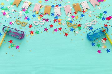 Party colorful confetti with noisemaker over light pastel blue wooden background . Top view, flat lay
