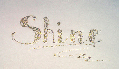 Glittering word - Shine - on paper in nostalgic colors, made with golden glitter