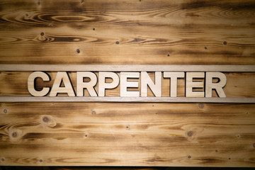 CARPENTER word made of wooden block letters on wooden board, top view.