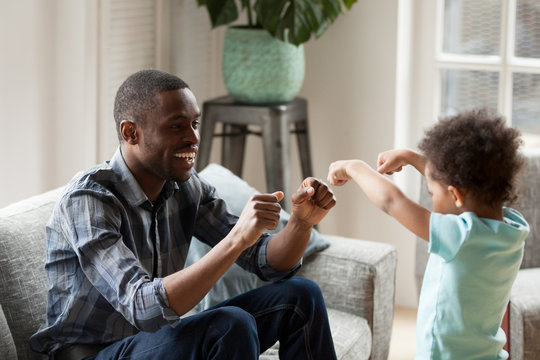 Happy black dad have fun playing educational game with toddler