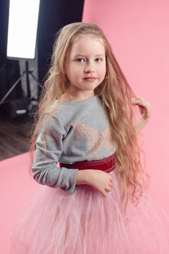 cute funny little girl with long blonde hair in photo studio in shooting process 