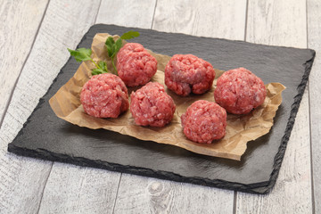 Raw meatball over wooden background