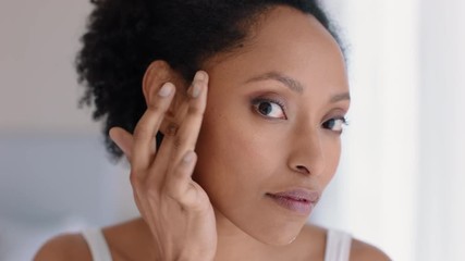 portrait beautiful african american woman looking in mirror at perfect skin enjoying natural complexion getting ready at home