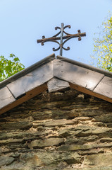 The iron cross on top of the roof of a little chapel in the Ardennes, Belgium