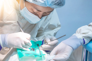 Female Asian dentist using instruments for examining and curing patient teeth in dental clinic. Dental procedure and medical treatment.